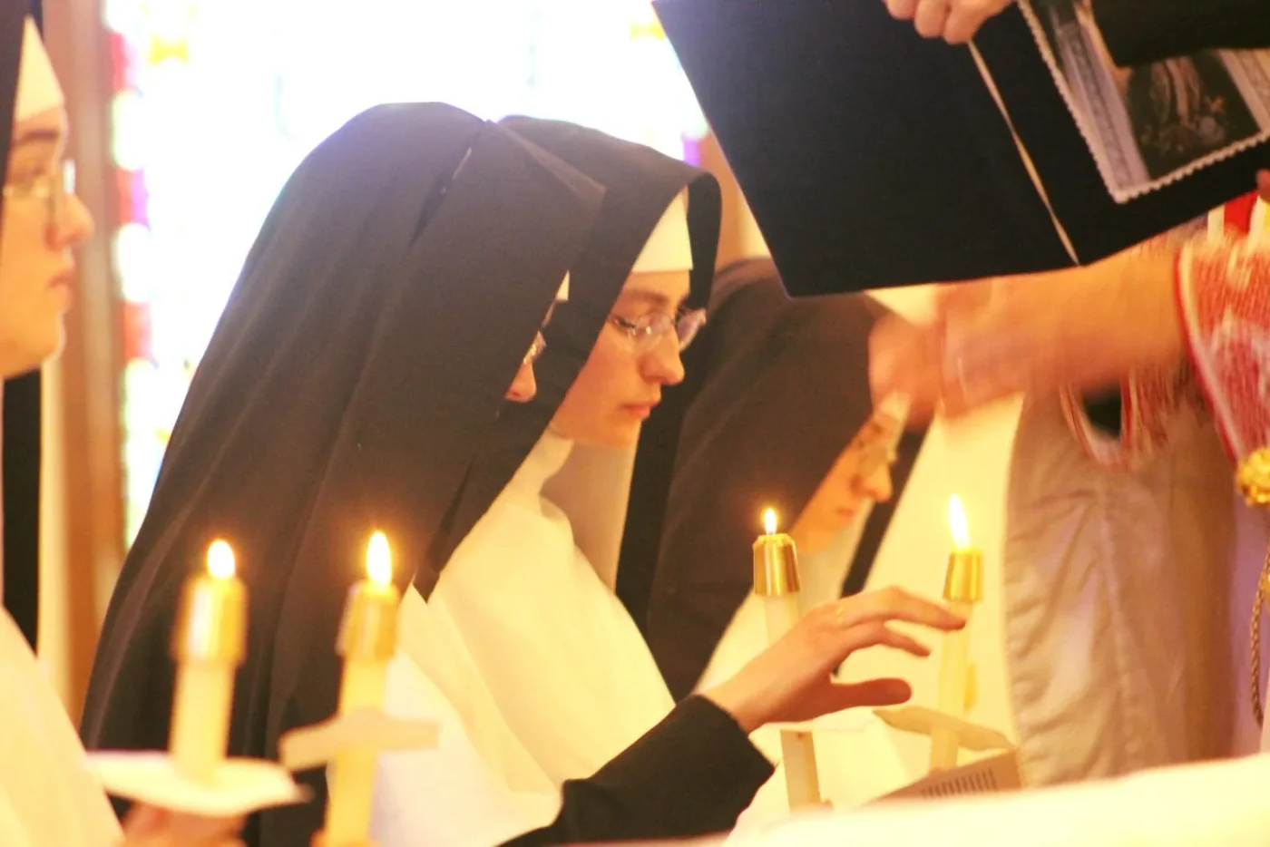 Professed Sisters with candles during a religious ceremony.