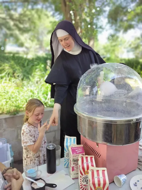 A Sister making cotton candy with children at Girls Camp.