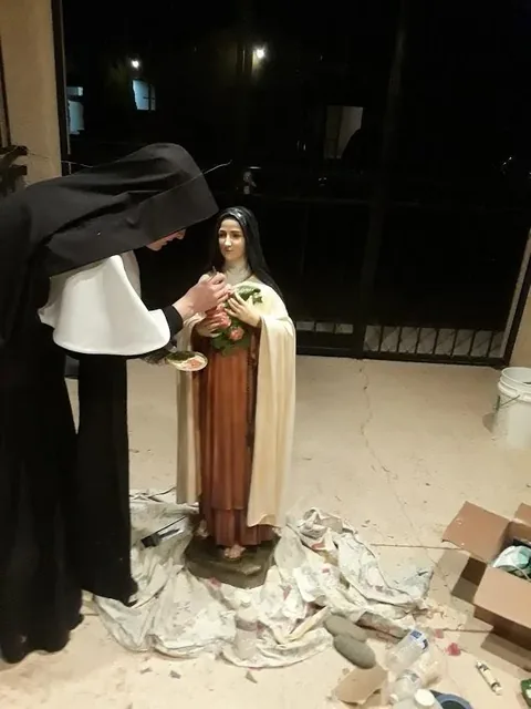 A Sister painting a statue.