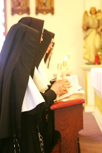 Professed Sisters holding candles during a religious ceremony.