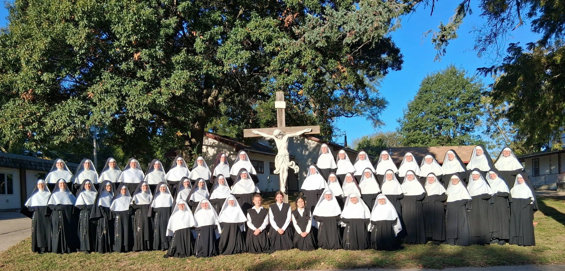 Sisters of the Congregation of the Mother of God gathered outdoors around a crucifix.